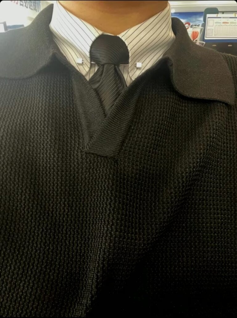 Classic men's outfit: striped shirt, black tie, and textured cardigan.
