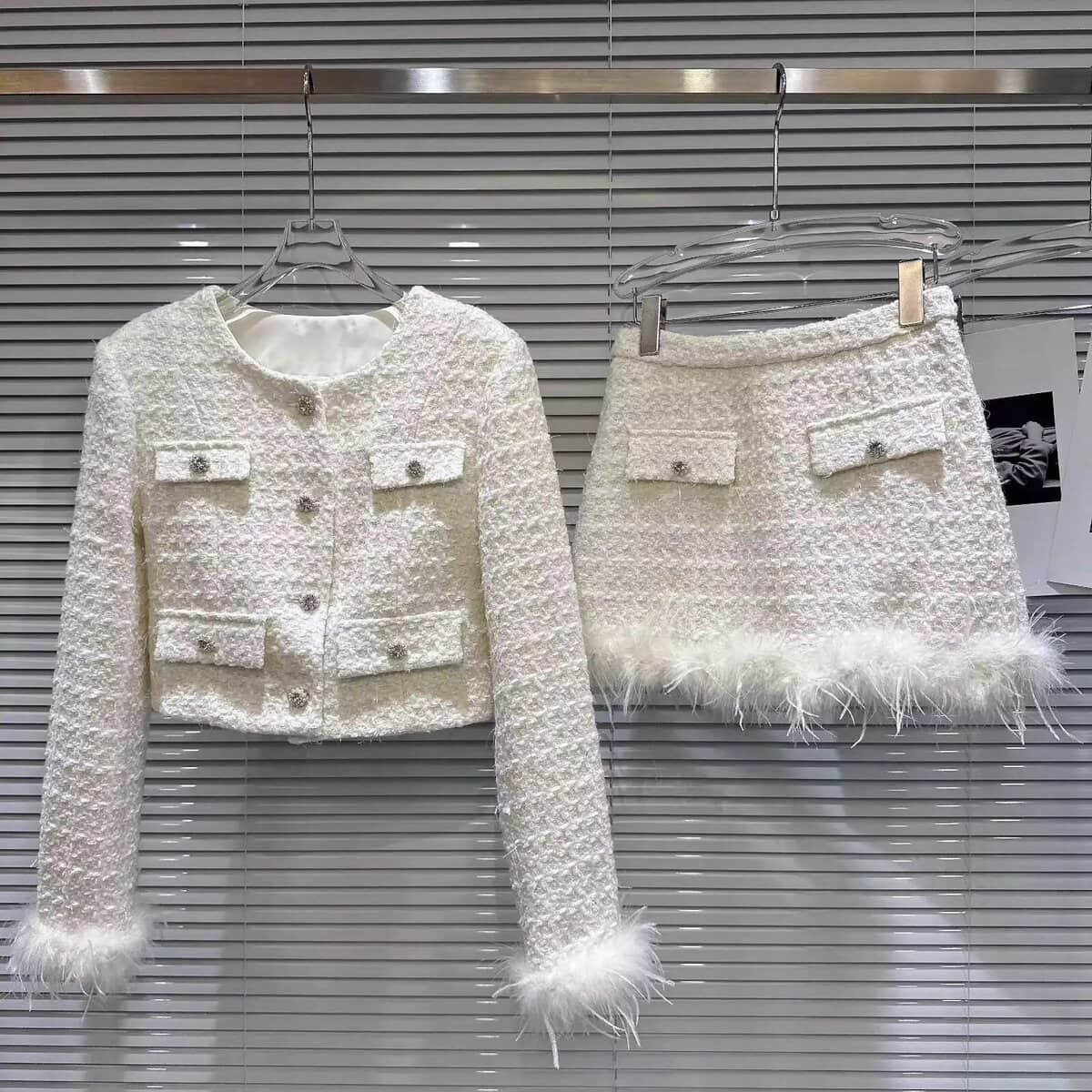 White tweed Chanel-style jacket and skirt set with feather trim, luxury old money outfit.