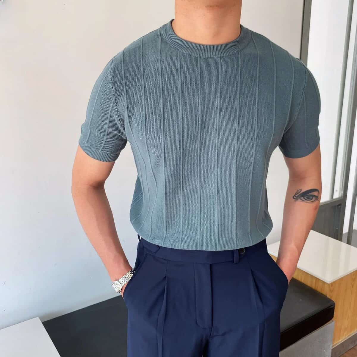 Man wearing stylish ribbed blue short sleeve t-shirt with navy trousers.